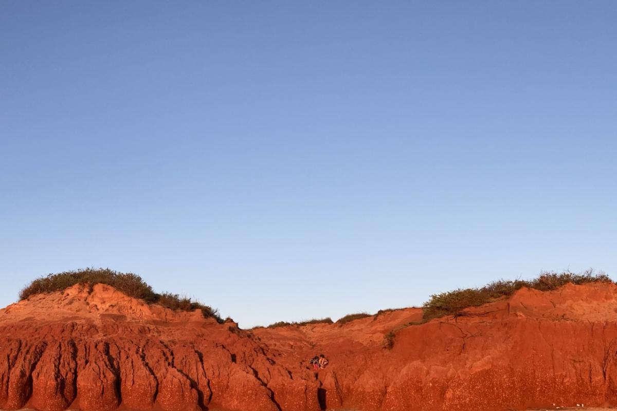 Red sand dunes against the blue sky. 