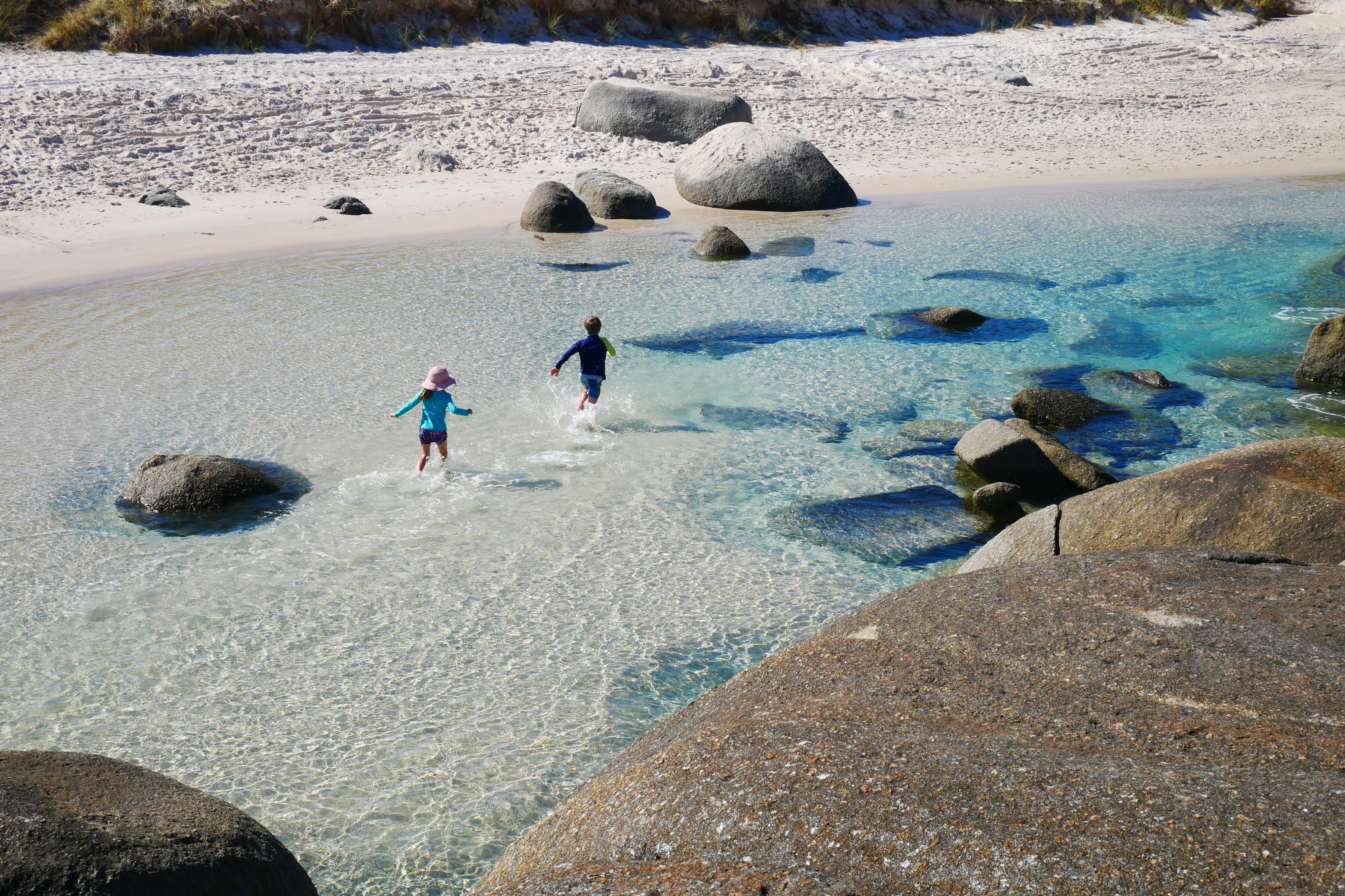 looking down on two children playing in clear blue water near beach