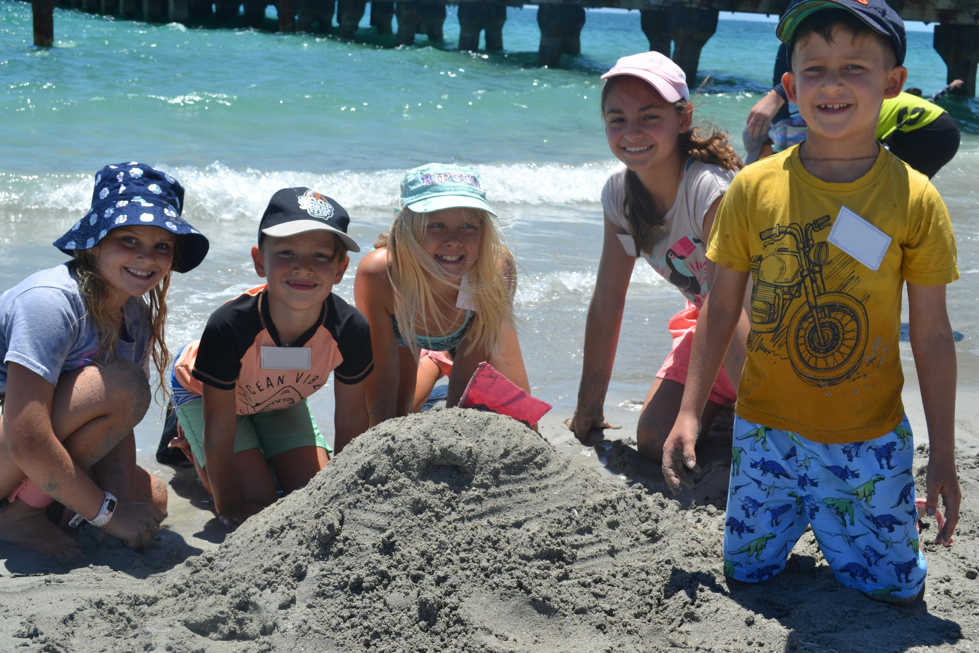 Children building a sandcastle at the nearer to nature holiday program. 