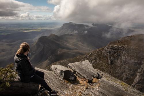 person sitting on mountain looking at view of peaks