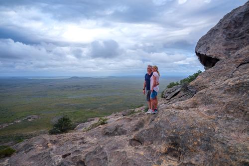 two people at the summit of a peak looking down onto a vast flat plain below