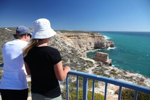 Visitors at lookout overlooking high cliffs jutting into the ocean.
