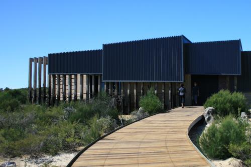 wooden footpath to a modern looking building set in bushland 