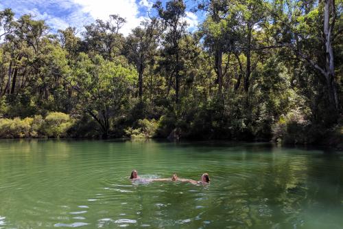 2 women swimming in a river pool surrounded by Jarrah/Marri forest