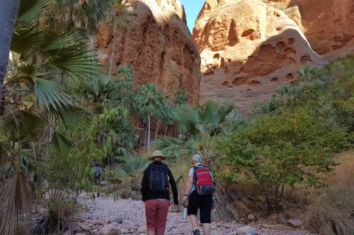 two people on a trail hiking up to eroded sandstone cliffs
