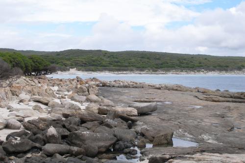Protected cove with trees close to the beach and rocky outcrop