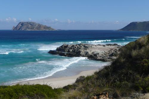 Rugged hills and white sandy beach with blue ocean and a island in the background