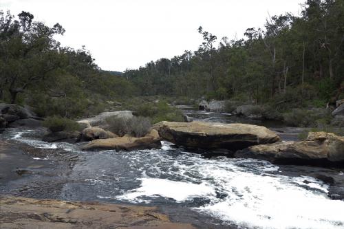 river flowing over big rock slabs of granite with forest in the background
