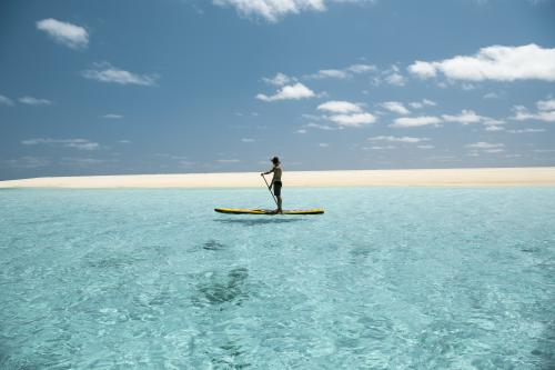 Woman on stand up paddle board on the clearest blue ocean
