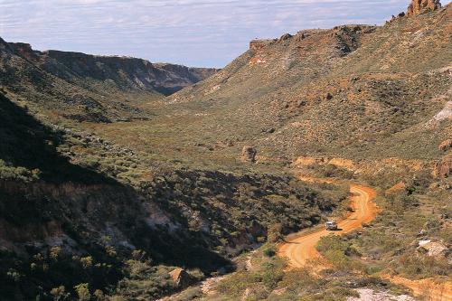 View of dirt track leading through canyon with a four-wheel drive