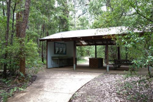 concrete pathway to a shelter for cooking and picnic tables surrounded by forest
