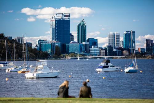 People sitting on shore looking at view of Perth city skyline