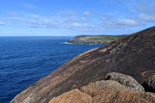 Round granite headland of Torbay Head with blue ocean and the cliffs of West Cape Howe in the distance
