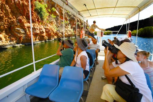 people on a boat tour on yardie creek close to the gorge rock wall