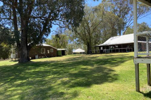 Quaint timber cottages set in a shaded grassed area.
