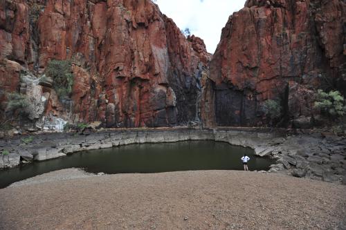 Visitor looking at the water of Python Pool surrounded by towering rocks