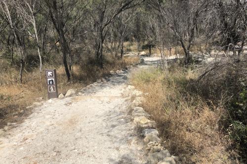 Dirt trail with signs pointing in the direction of the cave.