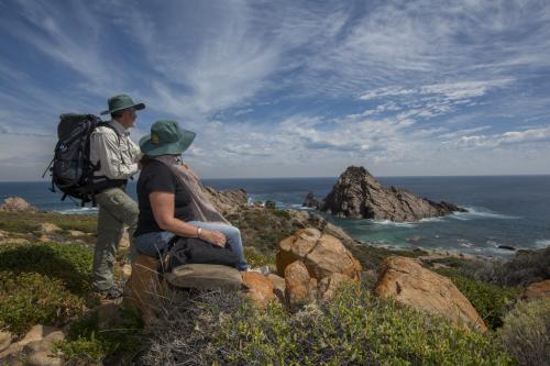 Two people with backpacks on resting on the Cape to Cape Track