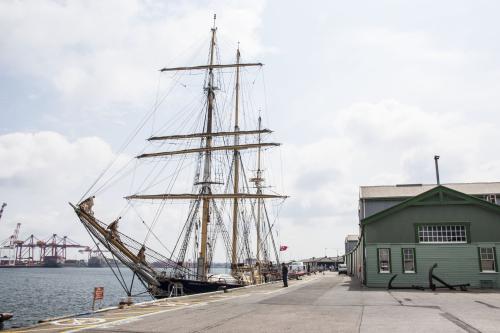 A tall mast sailing ship docked at the quay.
