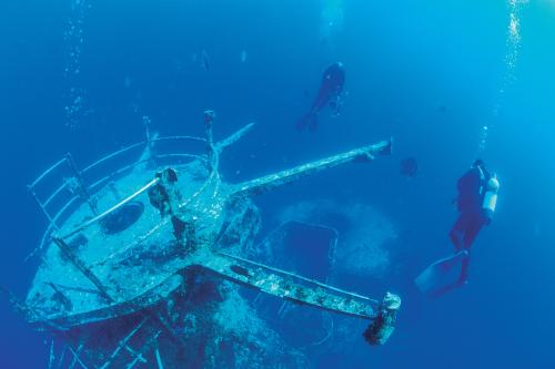 Scuba divers underwater near a sunken ship