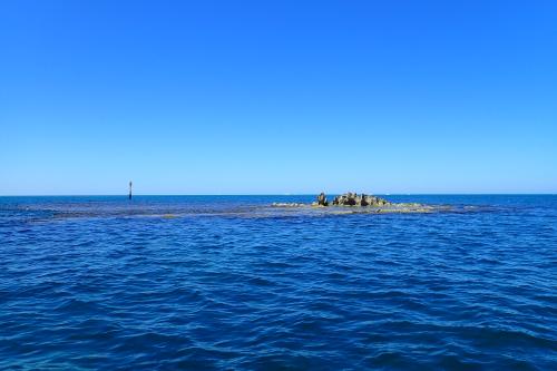 Wreck rock rises above blue ocean waters in a bright sky