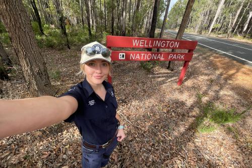 Person holding camera taking a selfie next to a sign. 