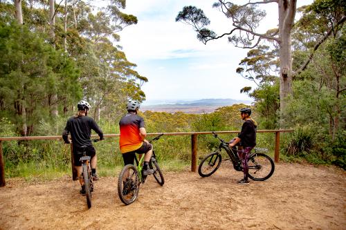Three people resting on bikes looking over a valley.