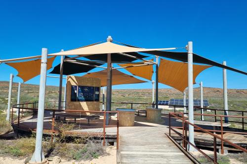 Shaded area with limestone wall and information panels. 
