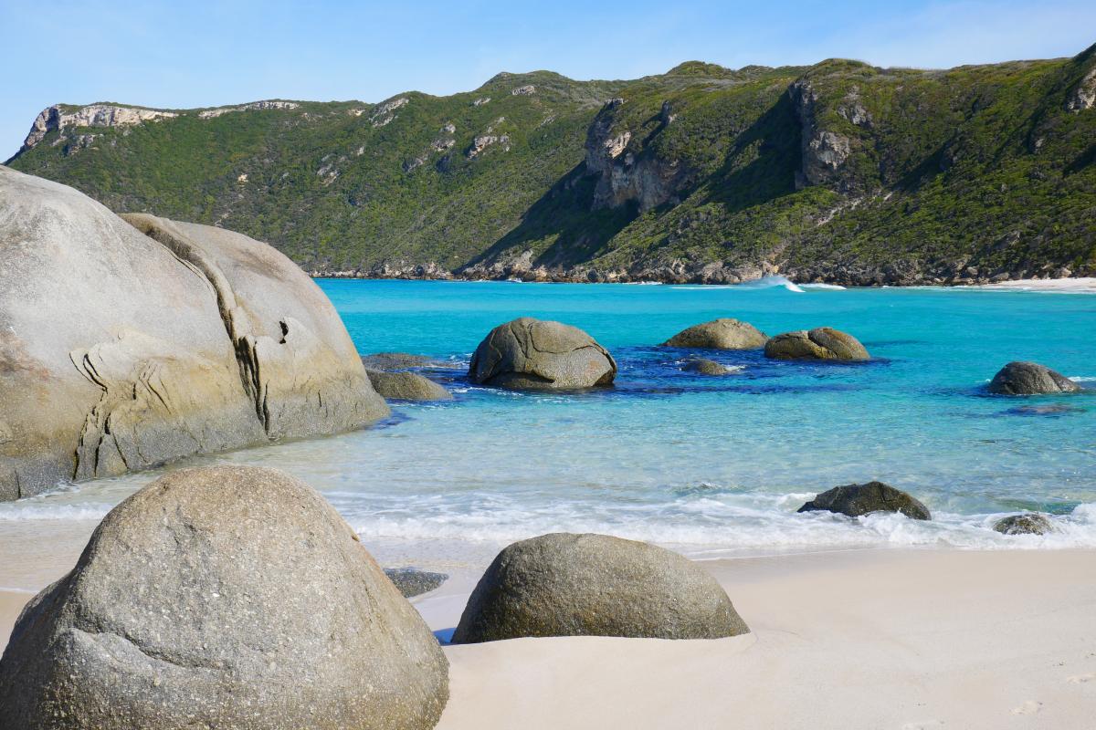 granite boulders surrounded by clear blue water near white sandy beach