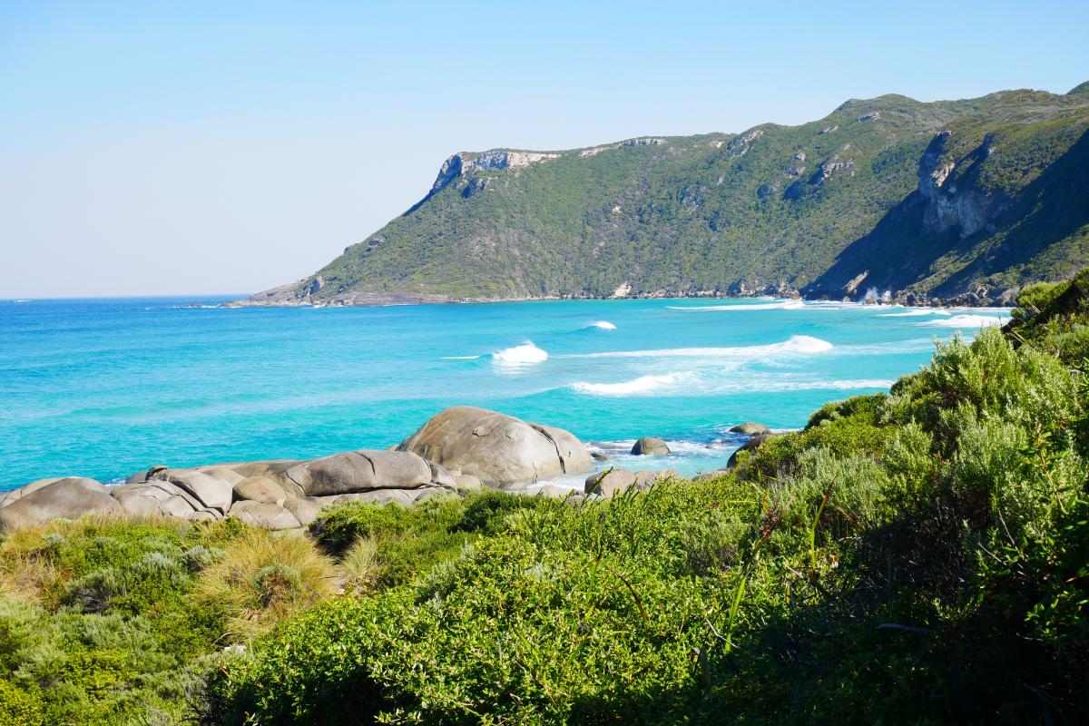 view of white capped waves rolling in with a headland in the background