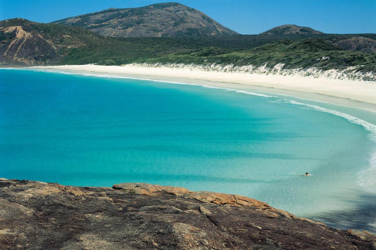 View from the rocky headland of the white sandy beach and turquoise water of