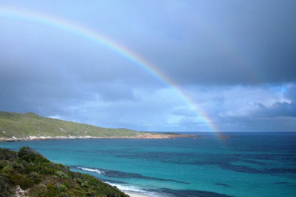 huge rainbow over blue waters of a sweeping bay