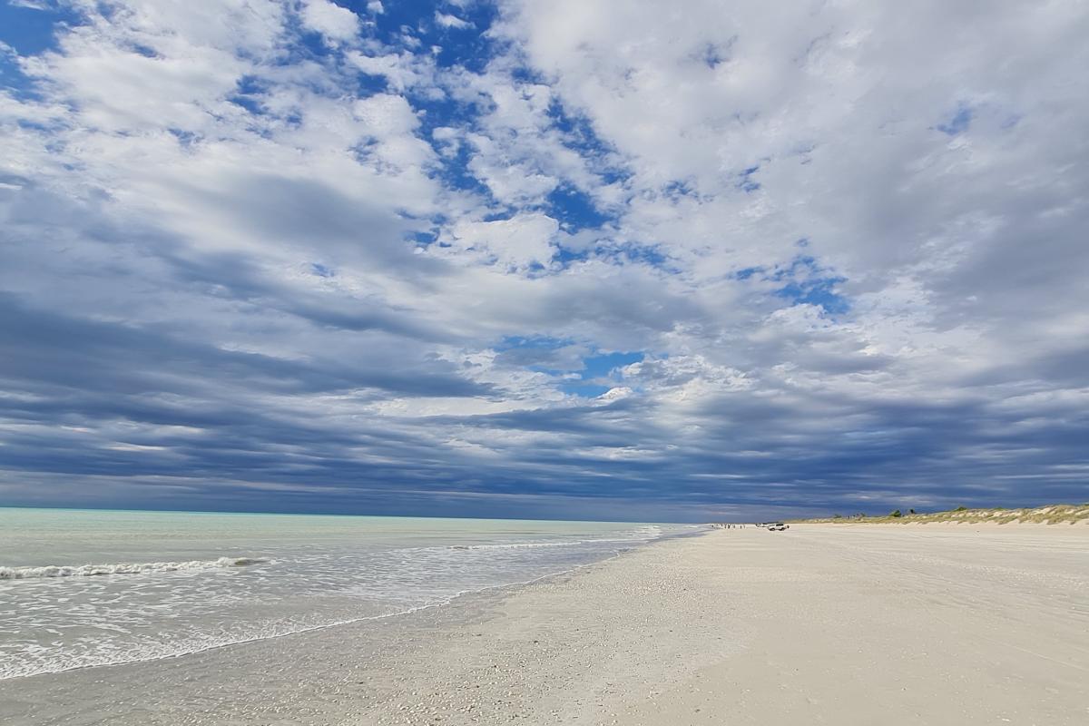 Eighty Mile Beach view of white sandy beach and blue water with blue cloudy skies