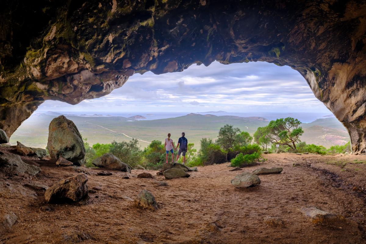 two people standing in large cave with a view