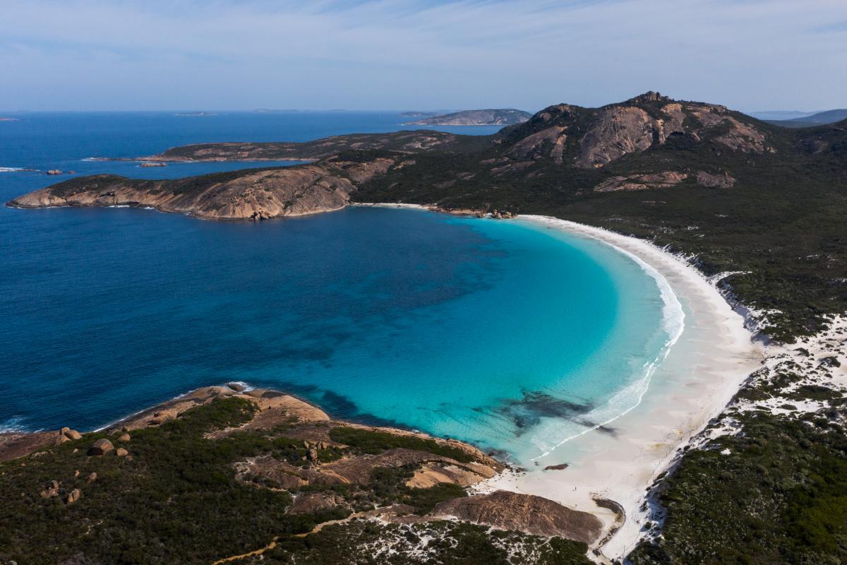 sandy beach with blue water surrounded by green vegetation