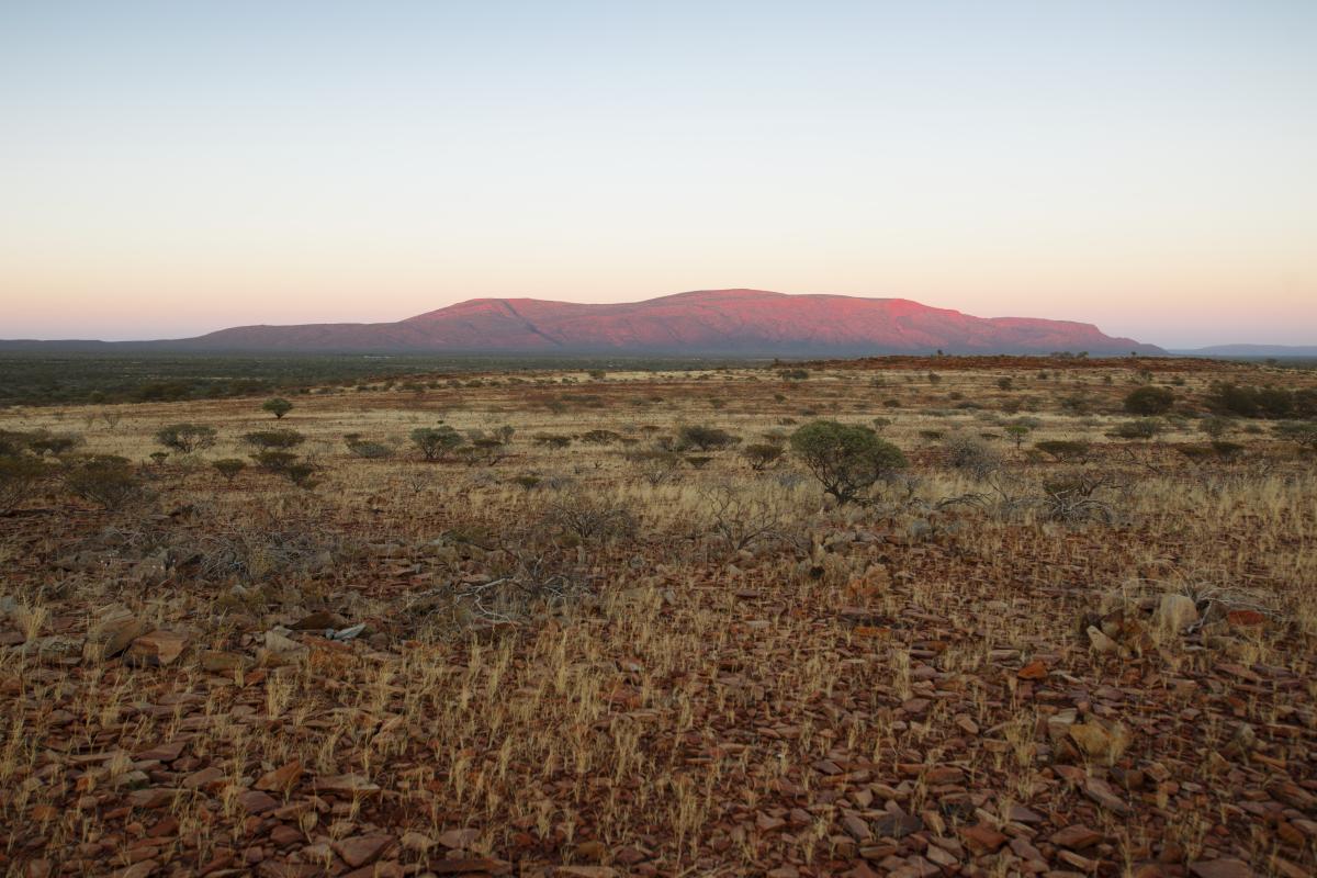 sunset view of a wide plain with a huge rock rising up in the distance