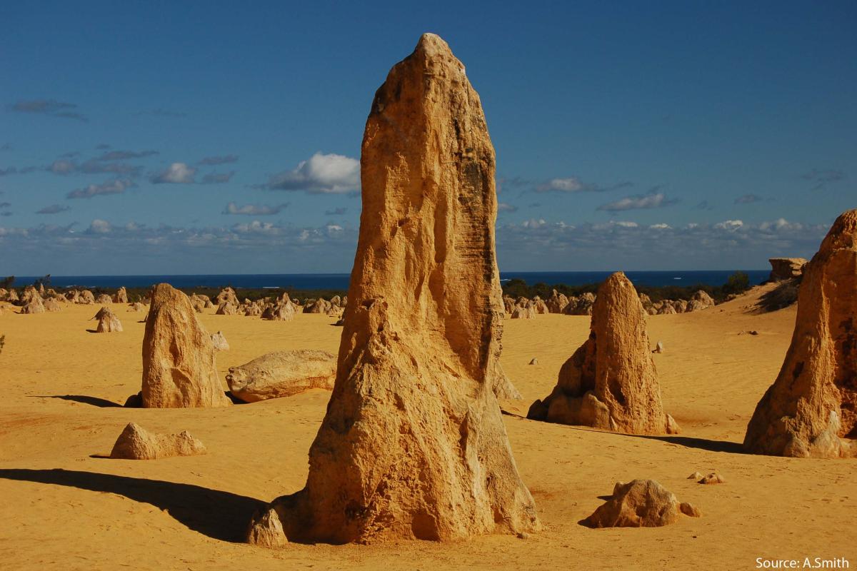 close up of an unusual rock formation in a desert landscape with the ocean in the far distance
