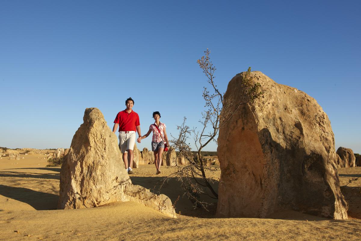 two people walking around unusual rock formations in a dune landscape