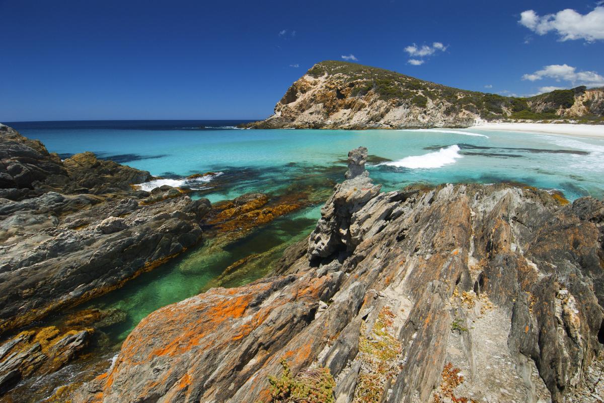 Quoin Head view of rocks and clear green ocean water with small white cap waves