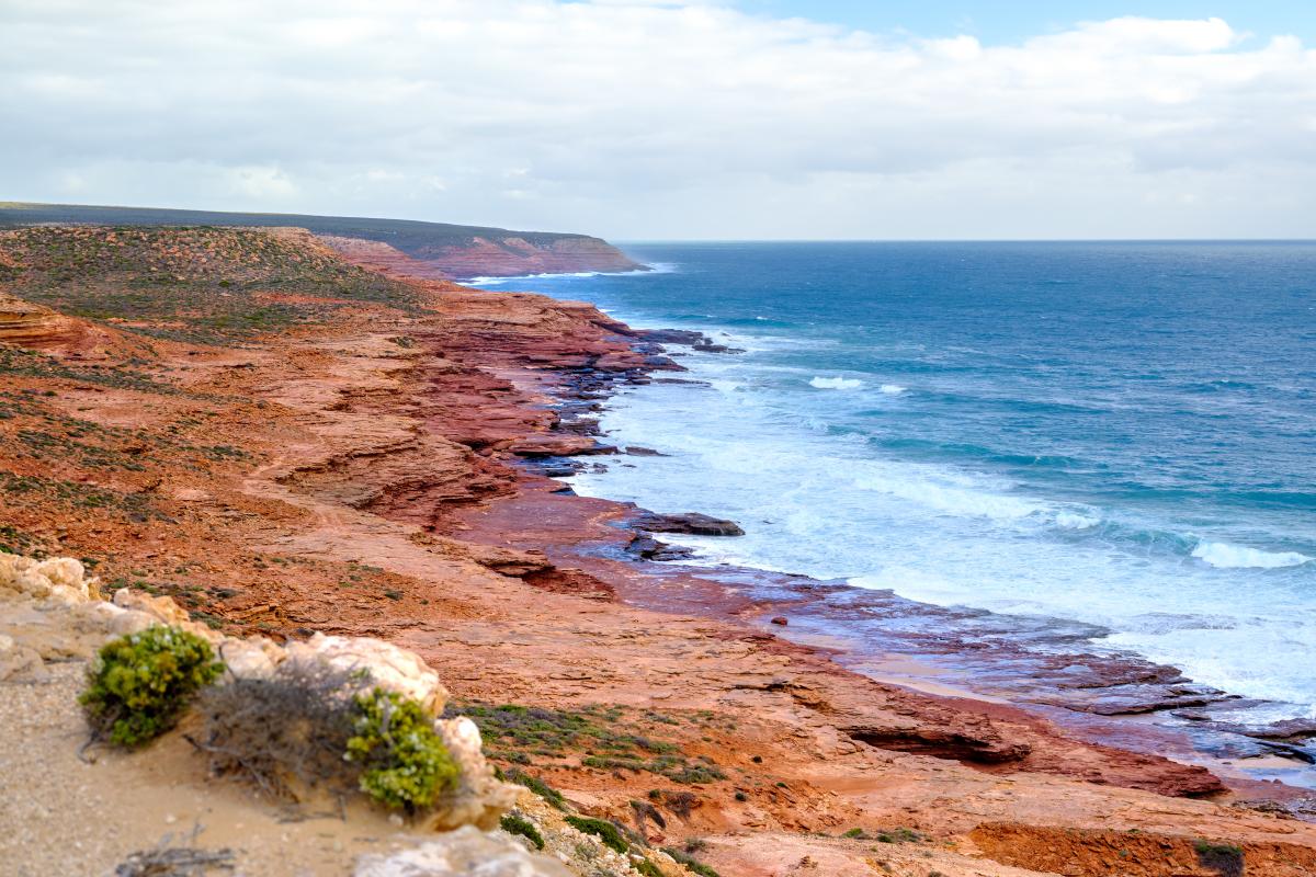 Rugged coastline at Red Bluff beach with contrast of red rock and blue water.