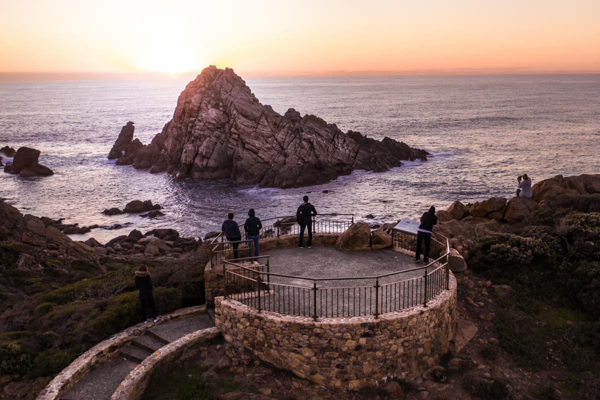 Looking out over a small island made of granite rock surrounded by the ocean with sun setting