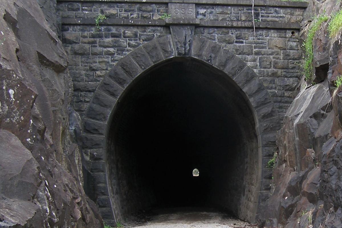 entrance to a man made railroad tunnel dated 1895 cut into granite rock wall