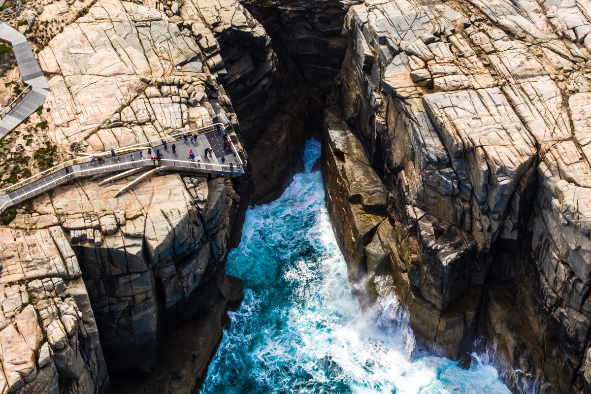 aerial view of metal platform sticking out over gap in rocks with the ocean below