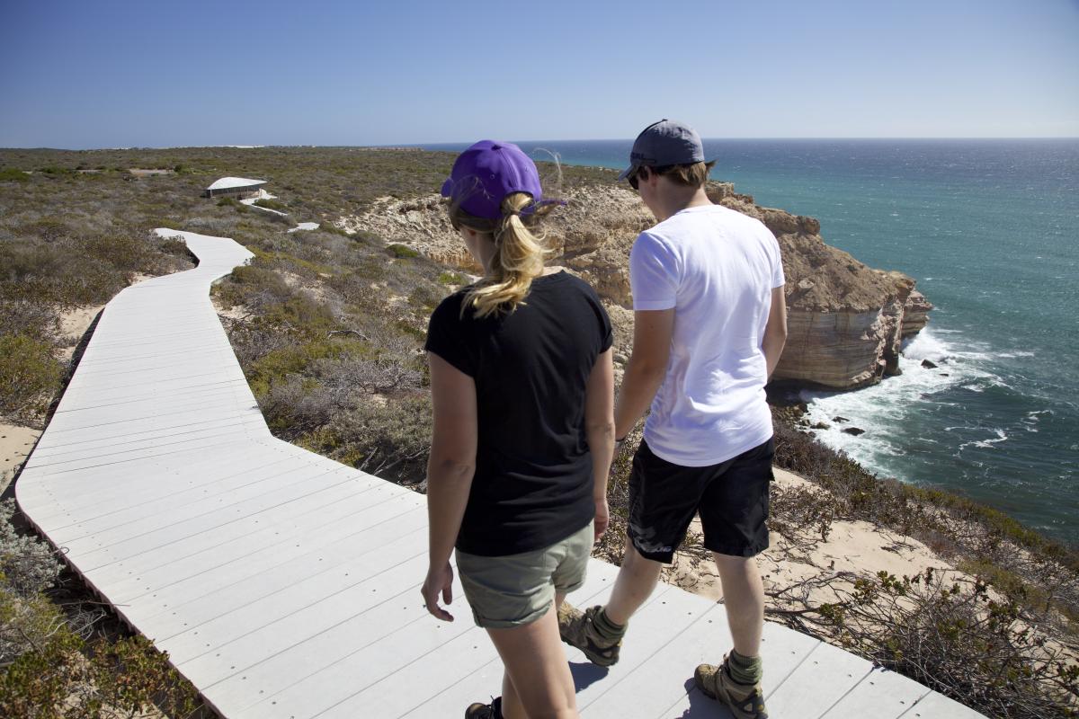 two people walking on a cliff top walk trail