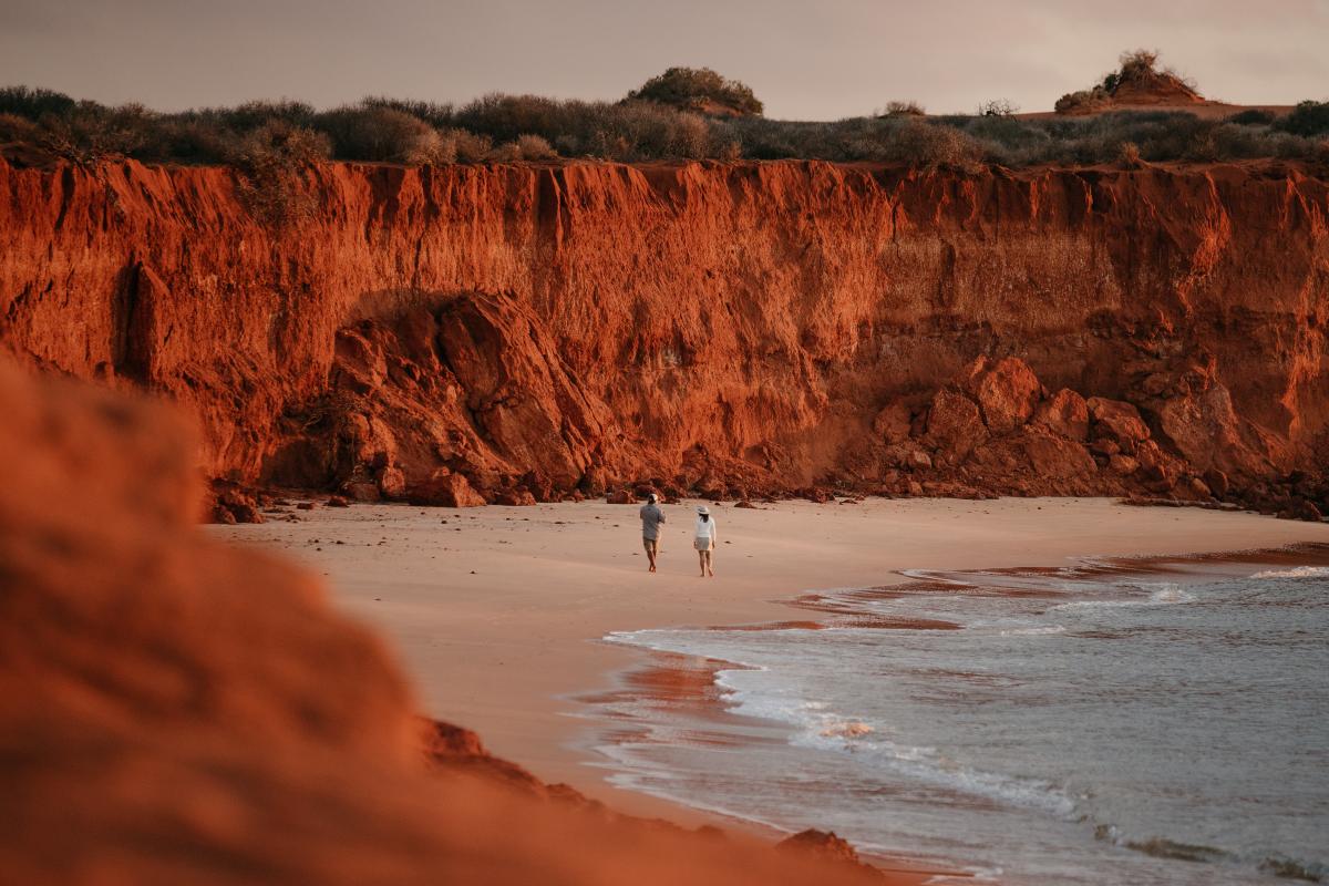 Visitors on beach with surrounding red rock wall towering above