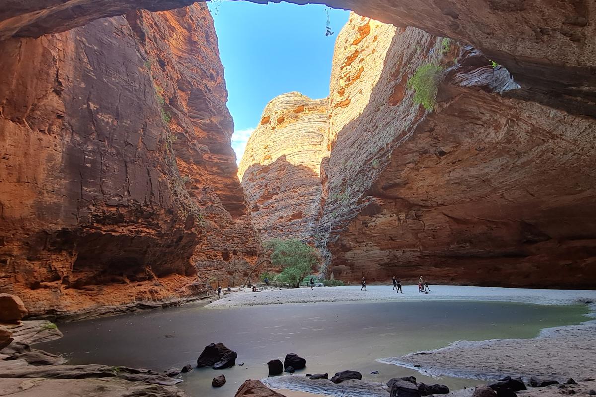 View from inside of Cathedral gorge looking across the water to visitors standing on the sandbank.