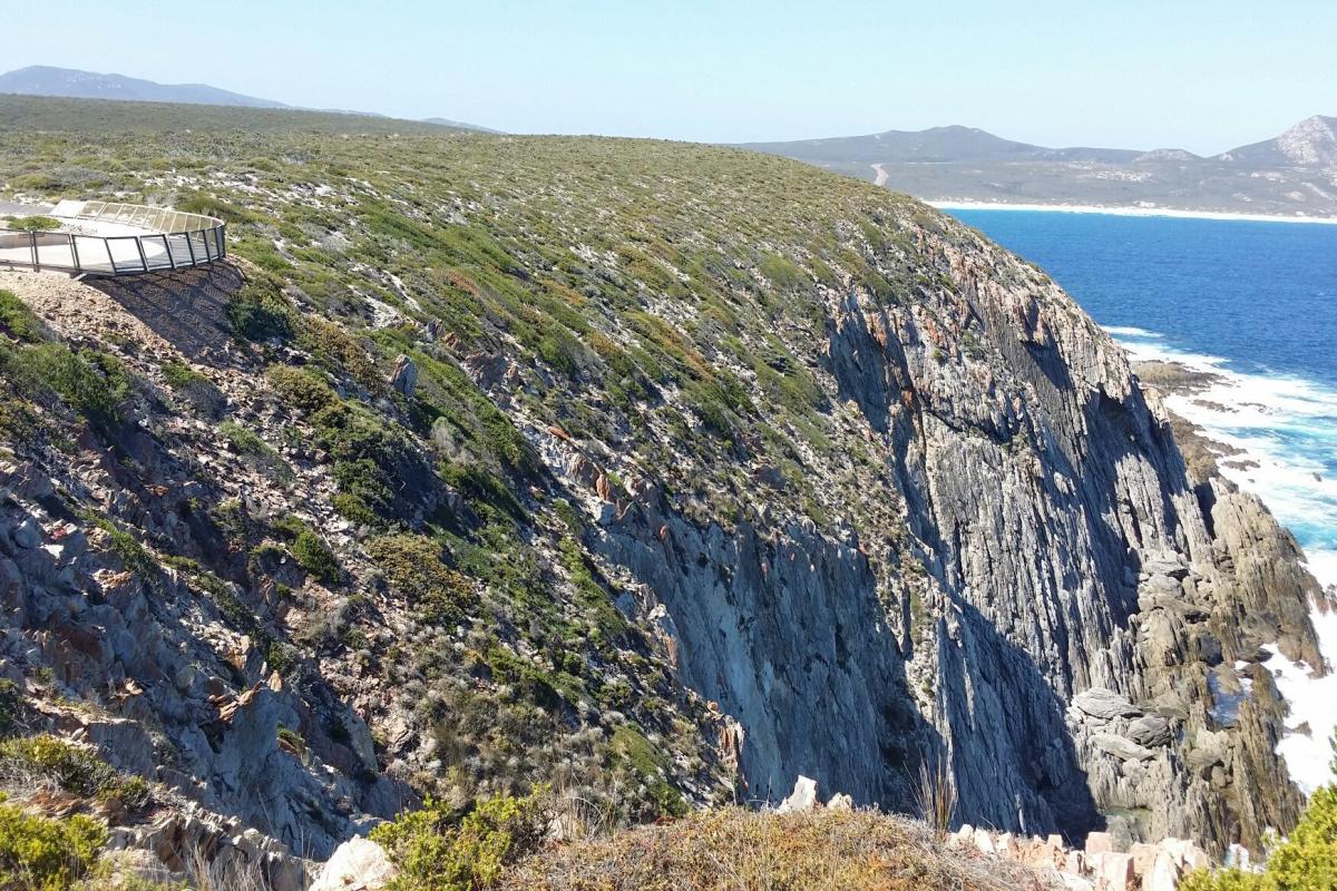 visitor viewing platform on a steep sided cliff descending to a rocky and churning ocean below