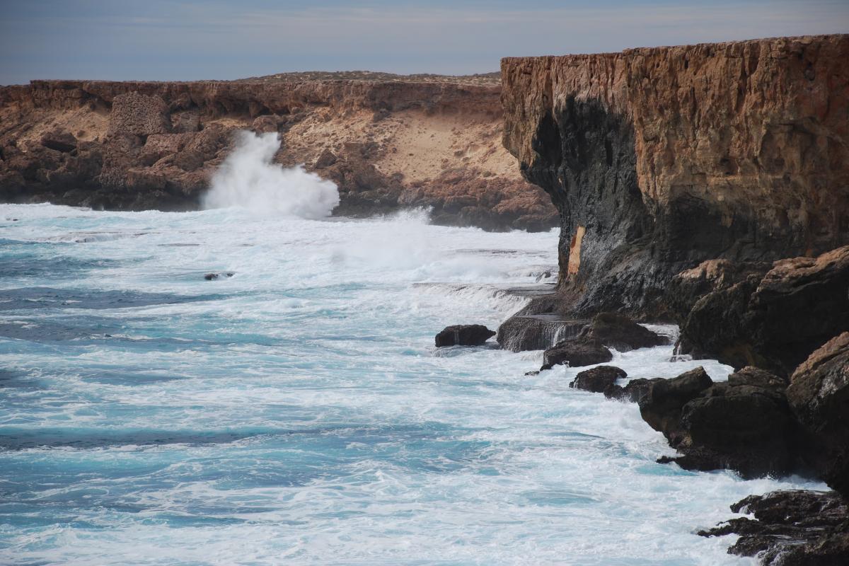 Rugged limestone cliff edges with large crashing waves