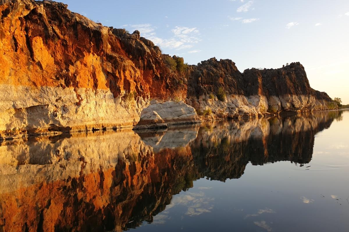 reflections of limestone cliffs onto the river surface with clear blue sky in the background