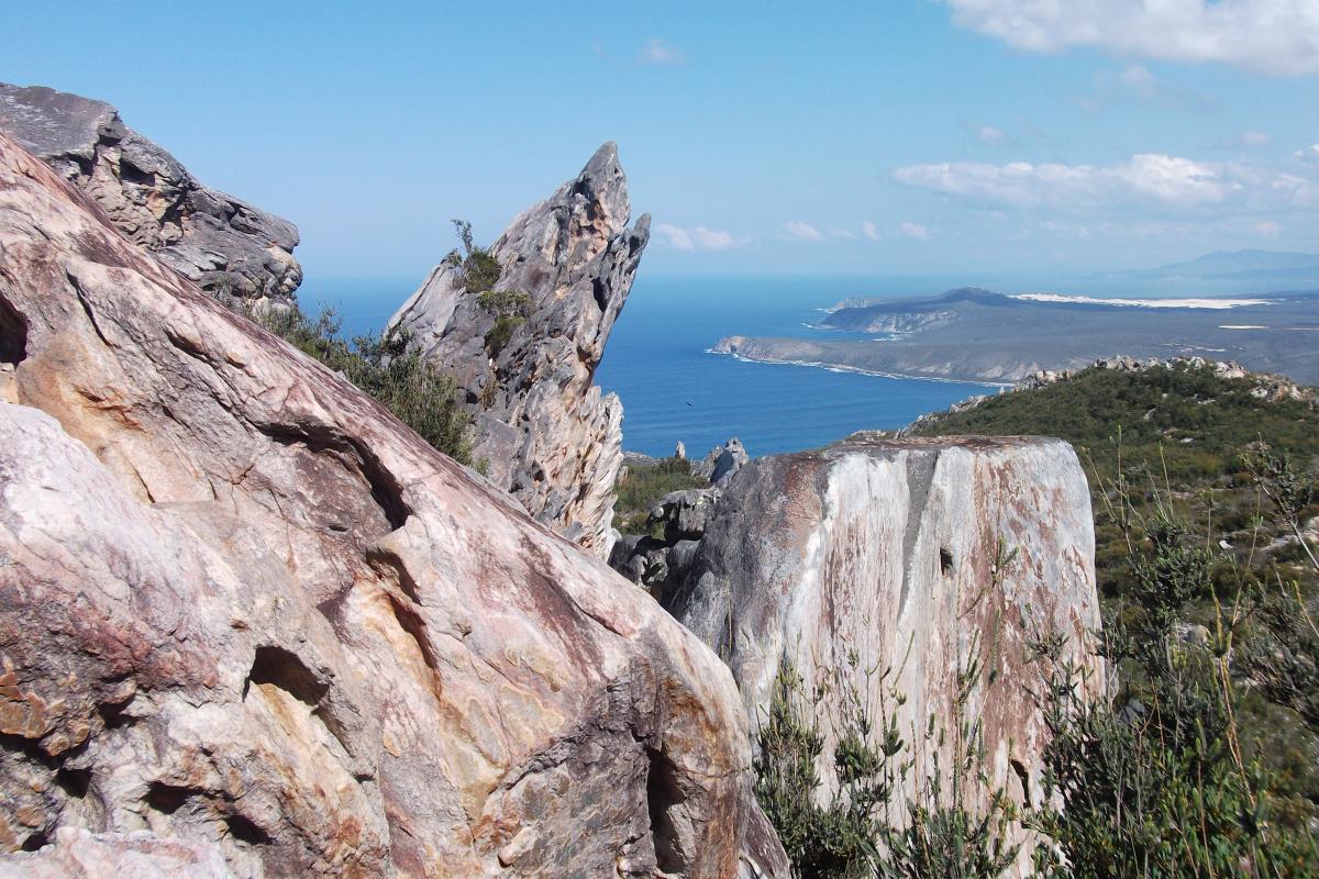 Imposing rock formations at East Mount Barren with a view in the distance to the ocean and rocky coastline below